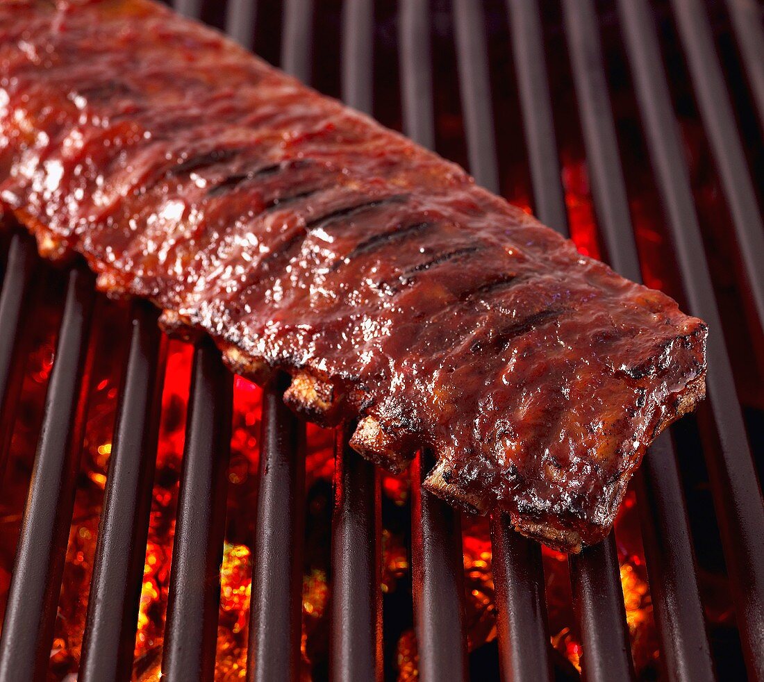 Whole Rack of Pork Ribs on Grill with Barbecue Sauce