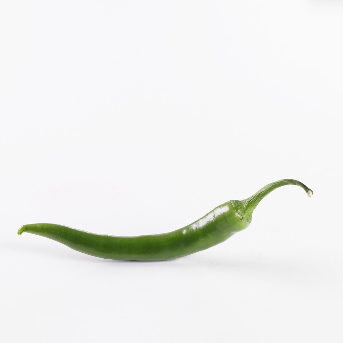 A green chilli against a white background