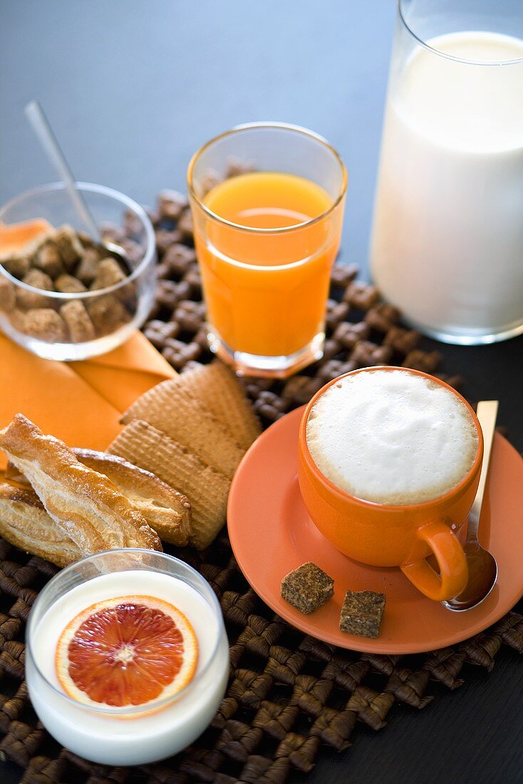 Italienisches Frühstück mit Saft, Cappuccino, Joghurt und Keksen