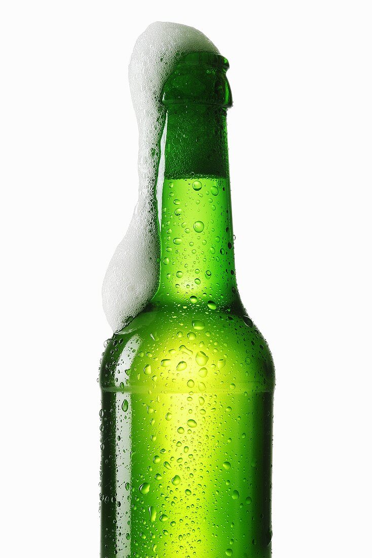 Beer frothing out of green bottle