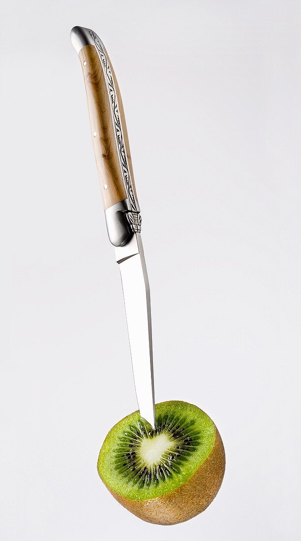 Knife sticking into half of a kiwi fruit