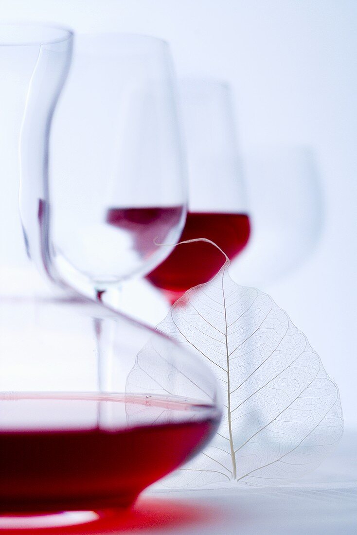 Glass of red wine, carafe and empty wine glasses