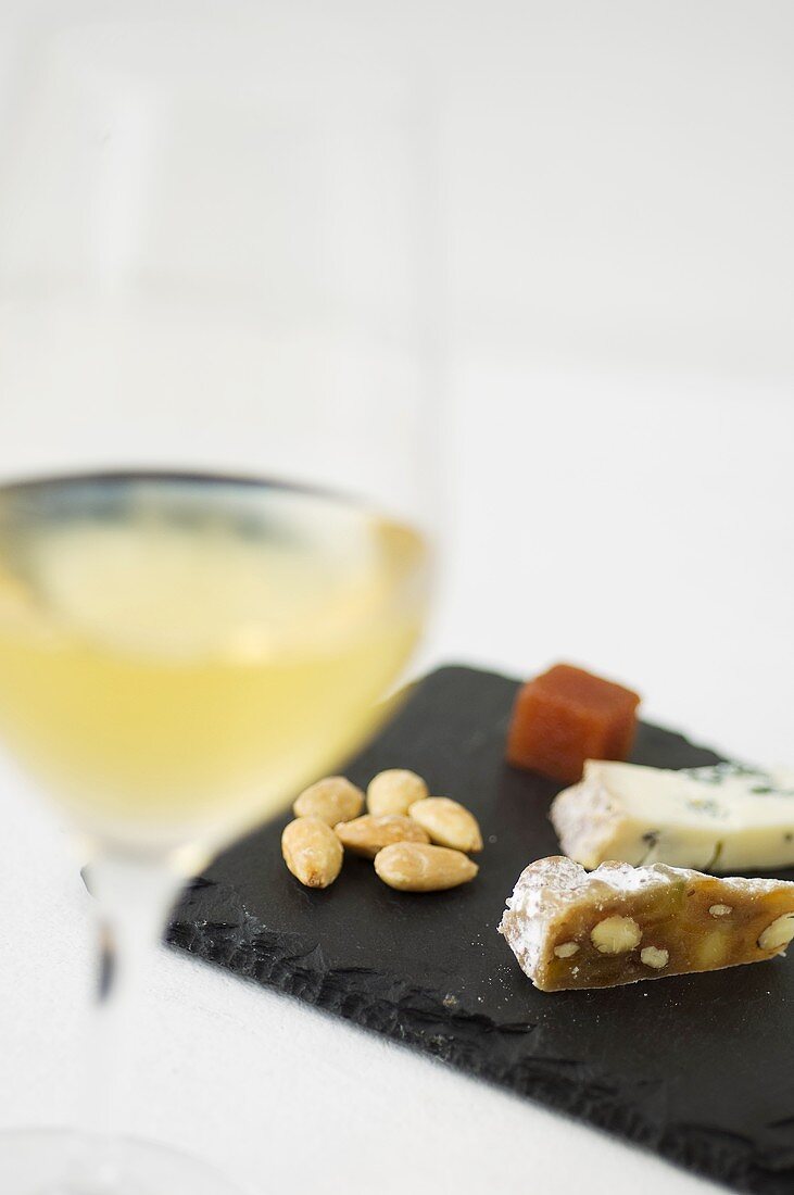 A glass of white wine, almonds and cheese