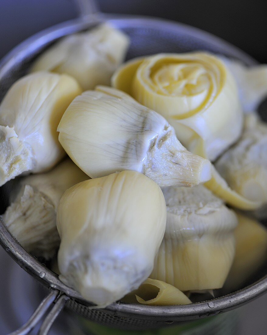 Tinned artichokes draining in a sieve