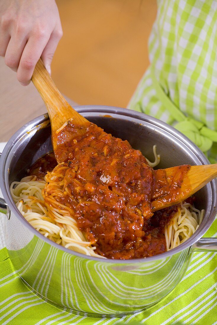 Mixing spaghetti with Bolognese sauce