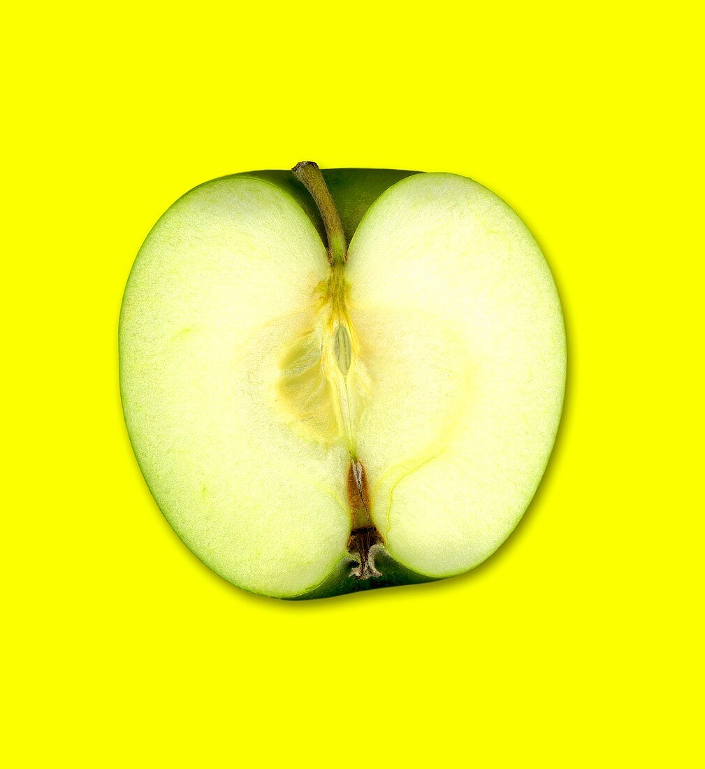 Ein halber Granny Smith Apfel vor gelbem Hintergrund