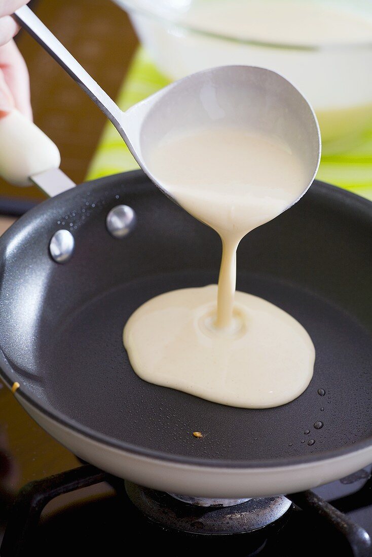 Putting pancake mixture into a frying pan