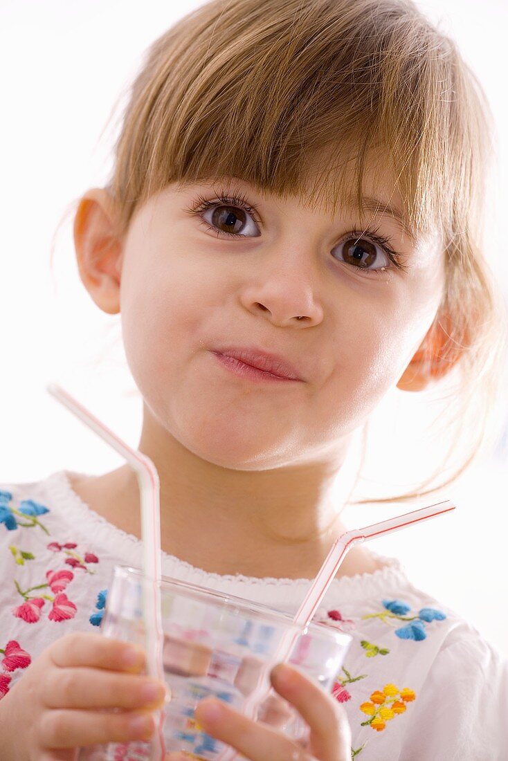 Little girl holding glass with straws