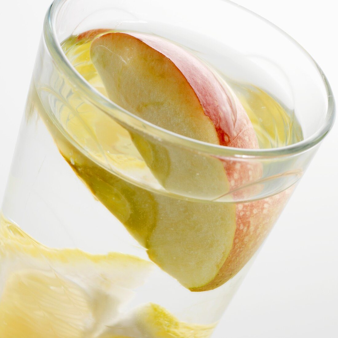 Ein Glas Wasser mit Zitronenschnitz und Apfelspalte