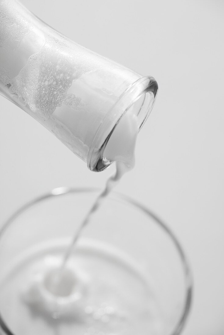 Milch wird aus einer Flasche in ein Glas gegossen