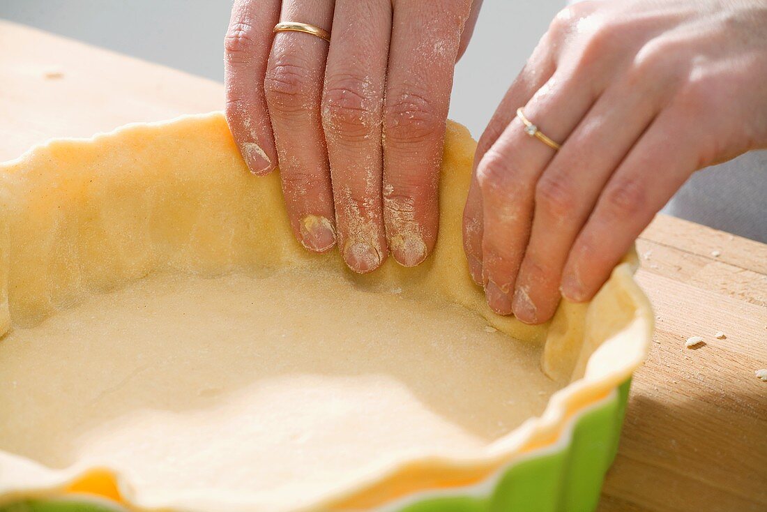 Making apple pie: lining a pie dish with shortcrust pastry