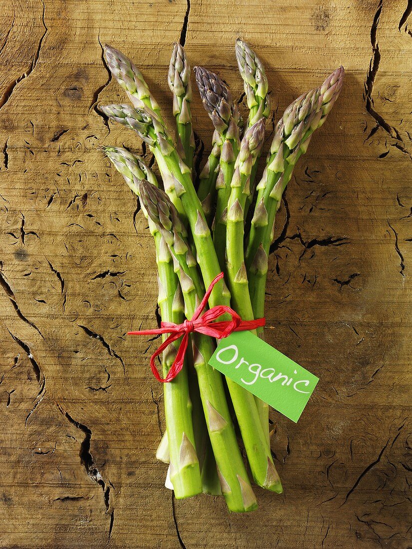 Ein Bund grüner Bio-Spargel auf Holzuntergrund