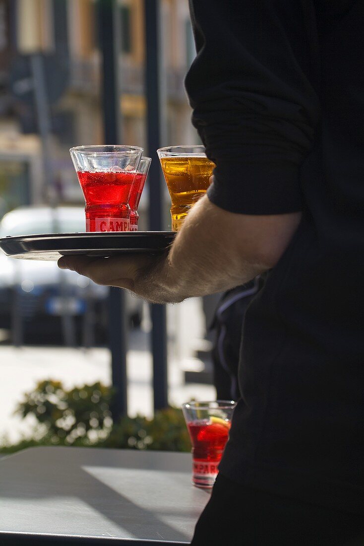 Kellner serviert Campari auf einem Tablett