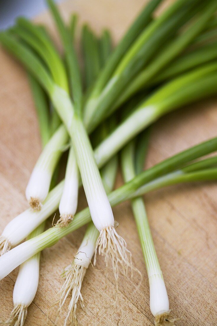 Several spring onions on a wooden board