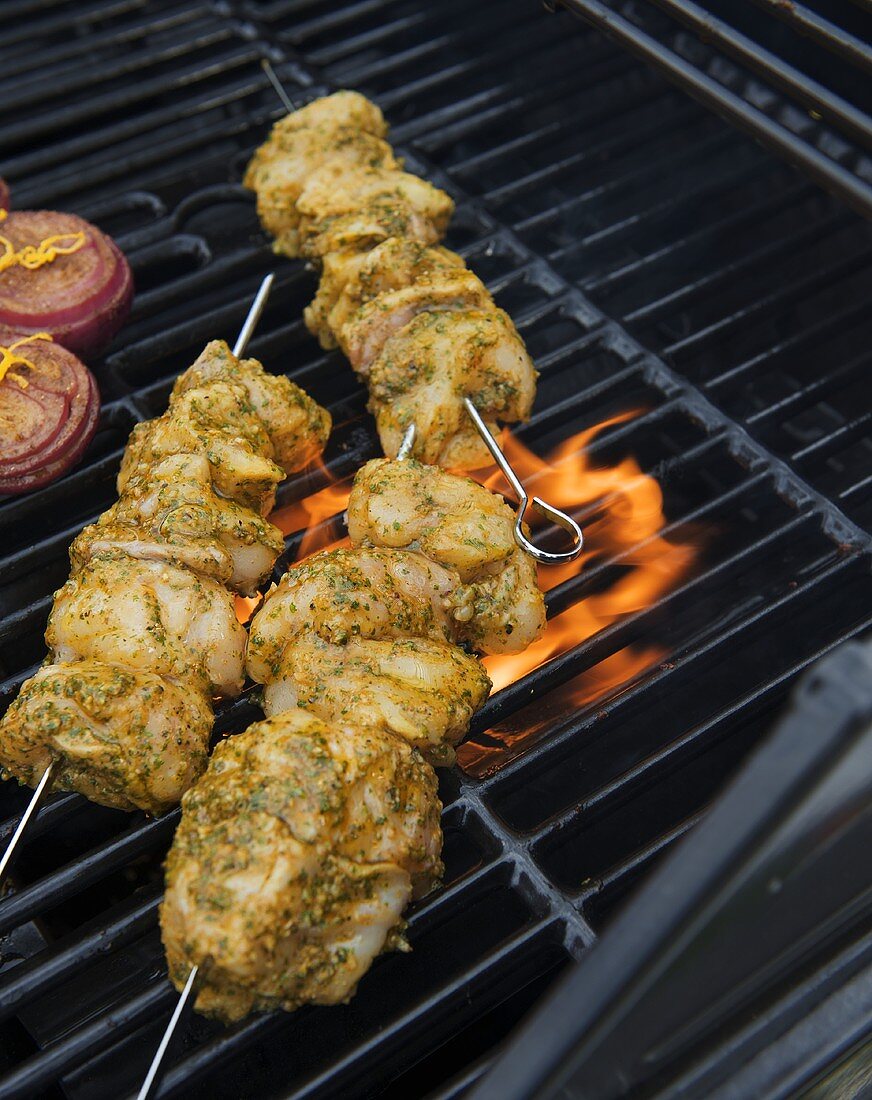 Marinated monkfish kebabs and onions on a barbecue