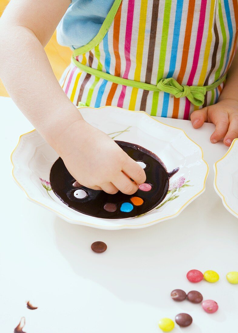 Girl decorating chocolate dessert with coloured chocolate beans