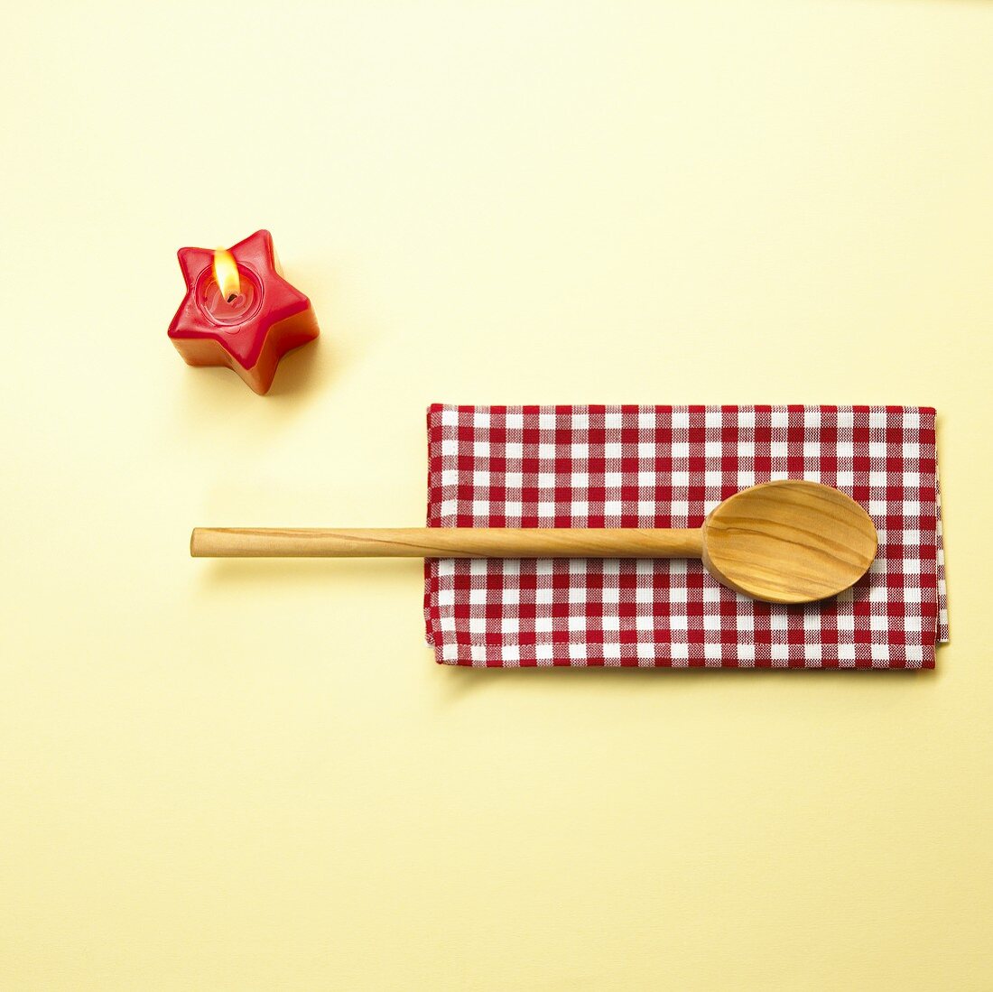 Wooden spoon on checked cloth, star-shaped candle