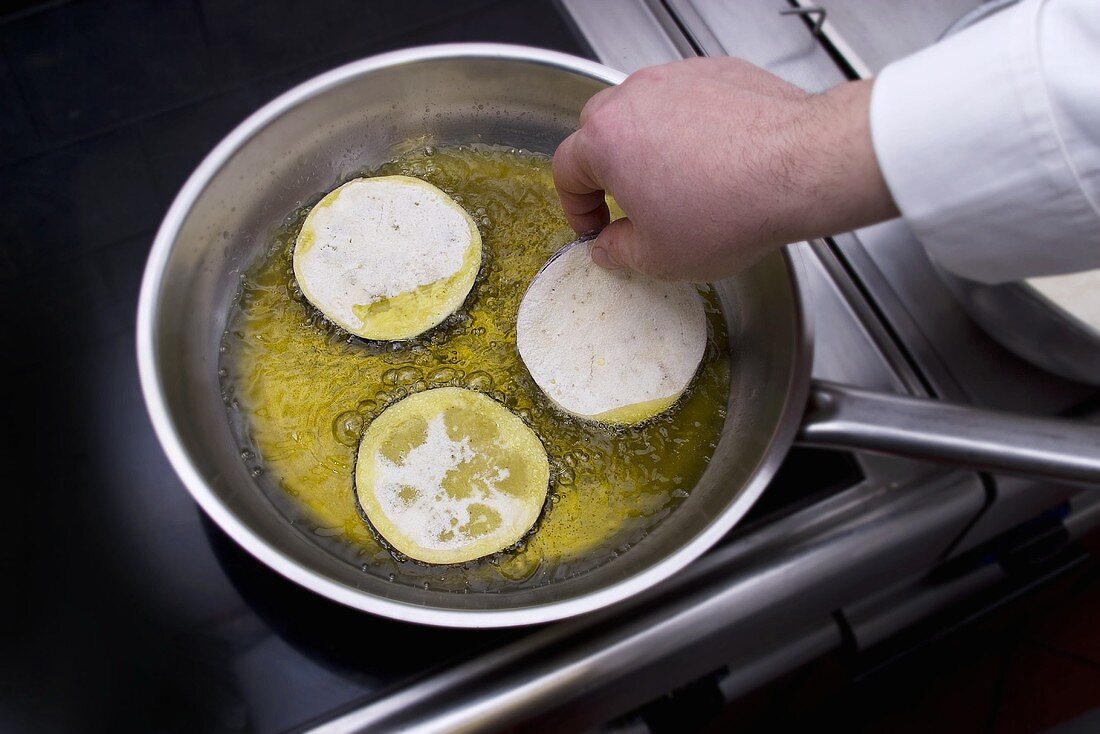 Frying aubergine slices in a frying pan