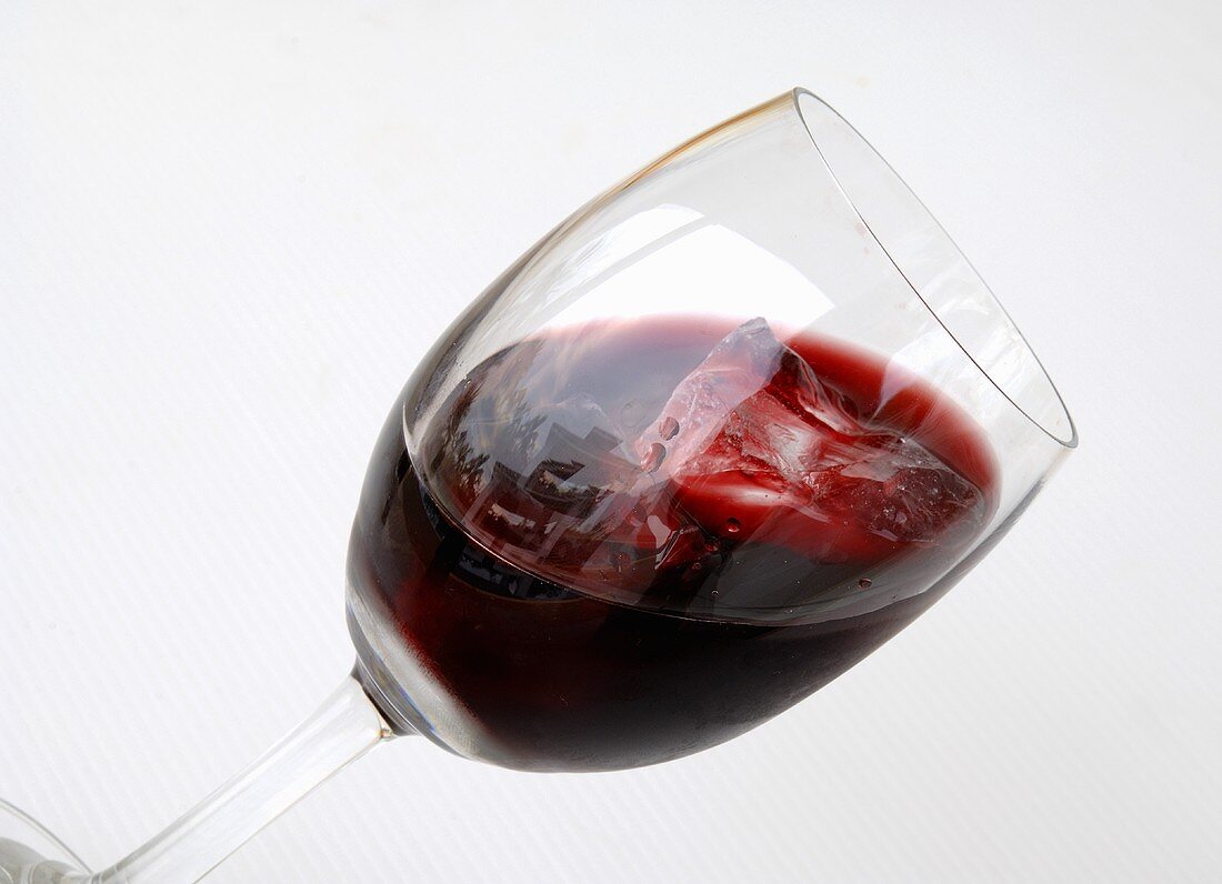 A glass of red wine with ice cubes