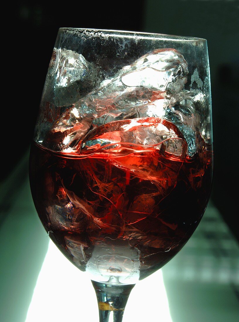 A glass of red wine with ice cubes