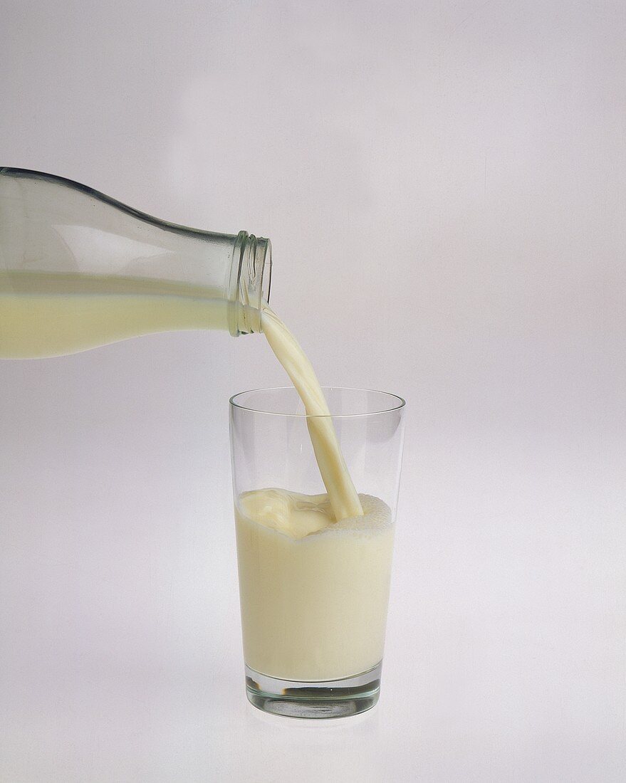 Milch aus Flasche in Glas gießen