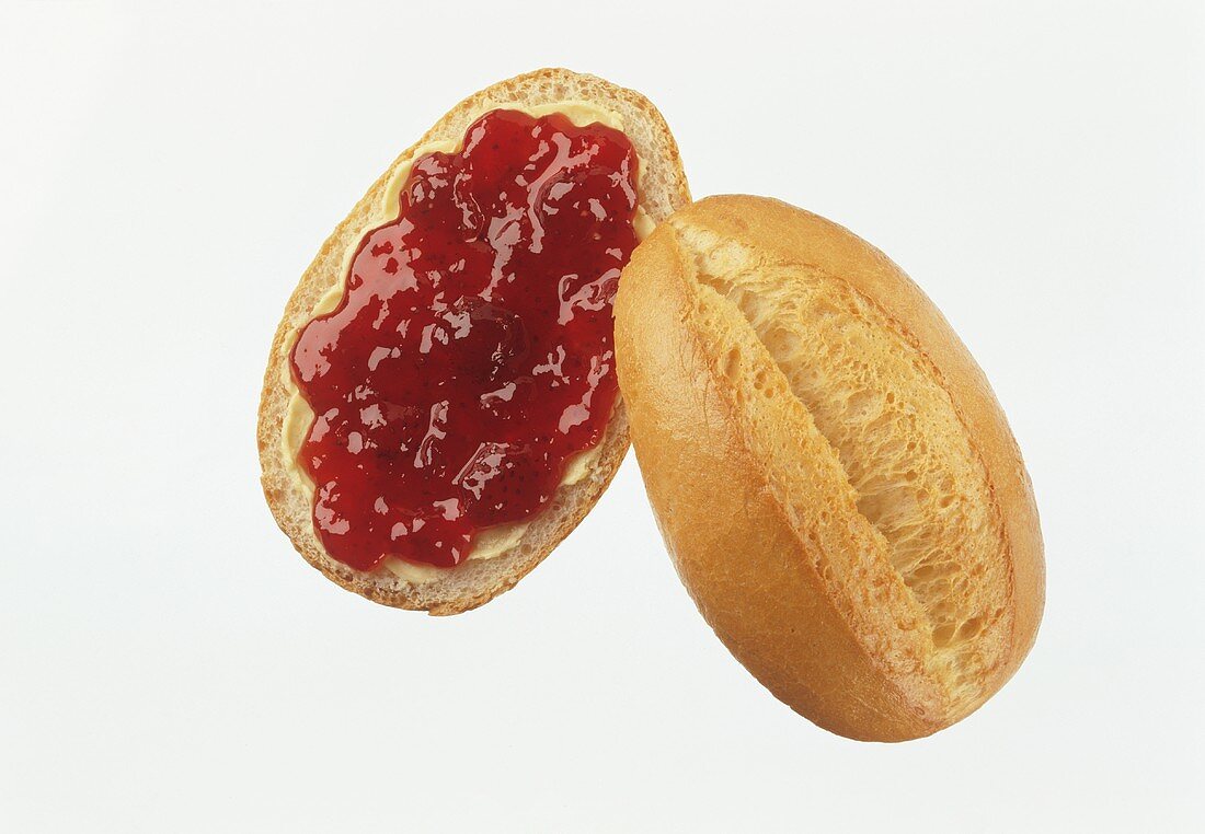 A bread roll with jam against a white background