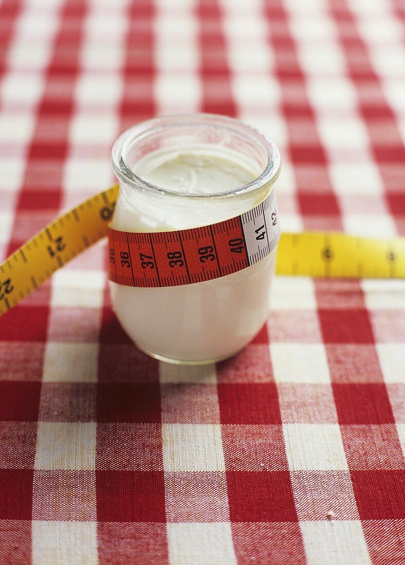 Ein Glas Joghurt mit Massband umwickelt