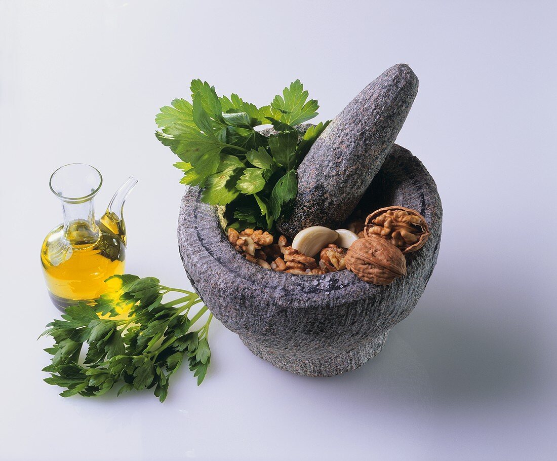 Mortar and pestle with ingredients for parsley pesto