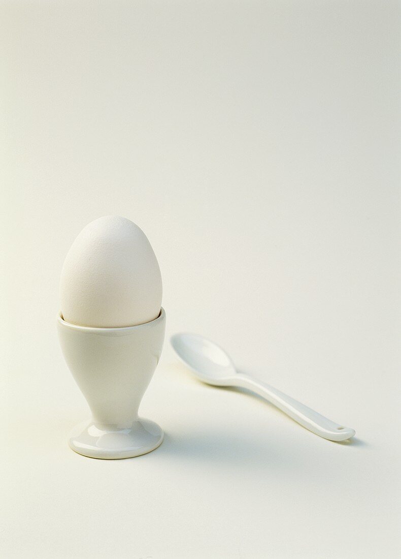 Ein gekochtes weisses Ei im Eierbecher mit Plasiklöffel