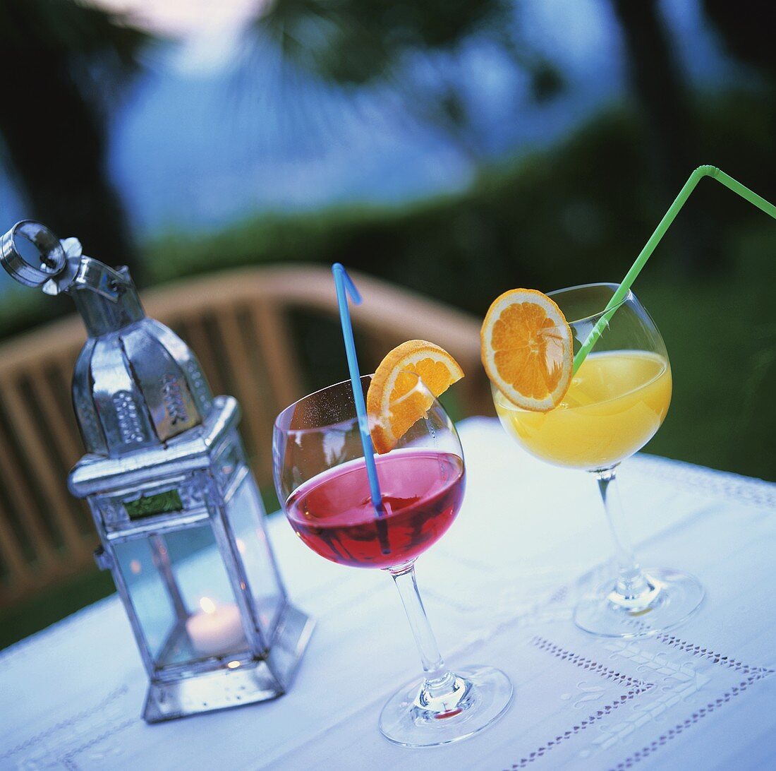 Two different juices in glasses on table at twilight