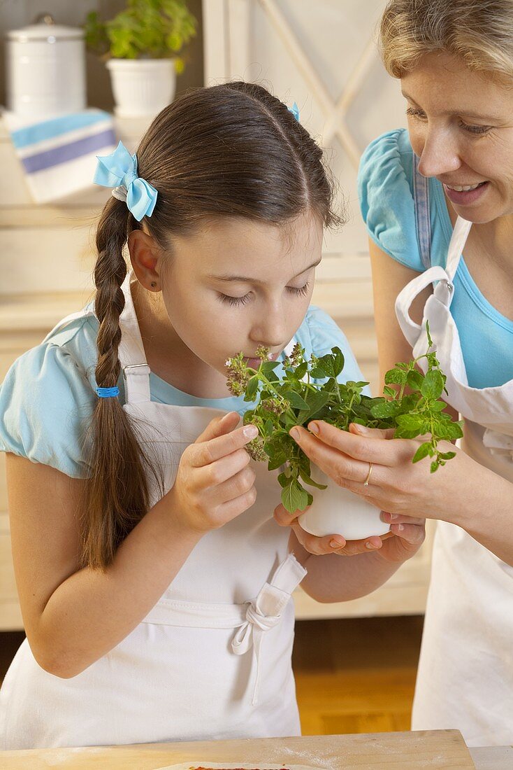Mother and daughter with fresh herbs in kitchen