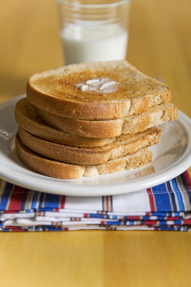Gestapelte Toastscheiben mit Butter vor Milchglas