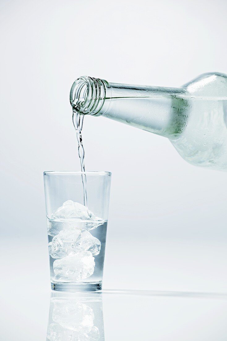 Wodka in Glas mit Eiswürfeln einschenken