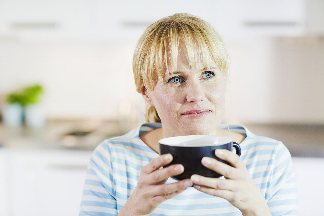 Blonde Frau hält grosse Teetasse
