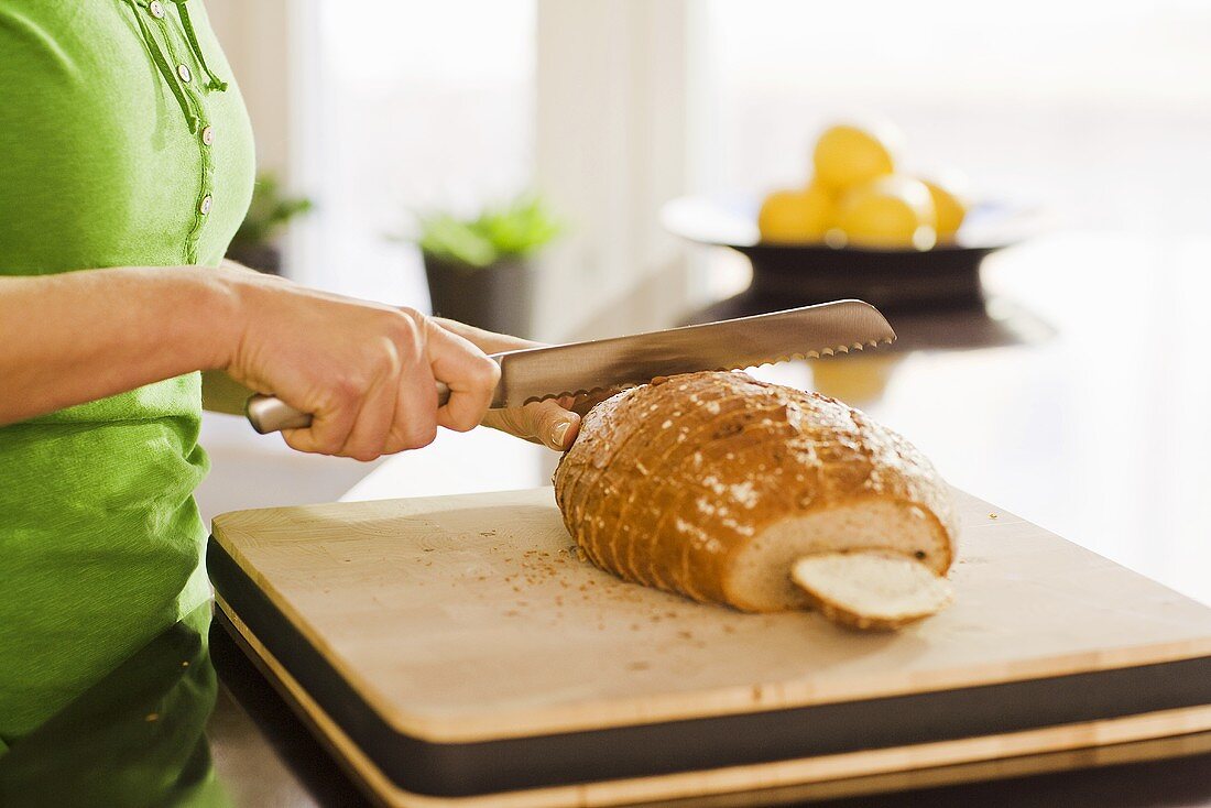 Frau schneidet Brot in der Küche