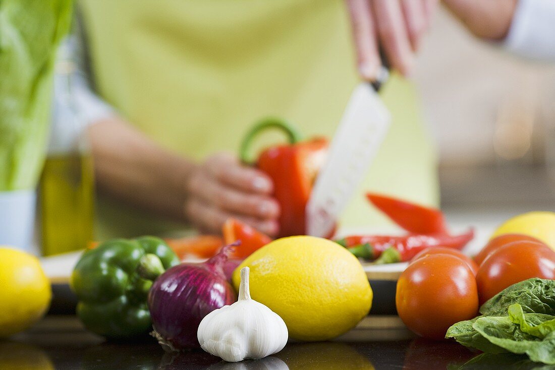 Gemüse und Zitronen in Küche, Frau schneidet Paprika