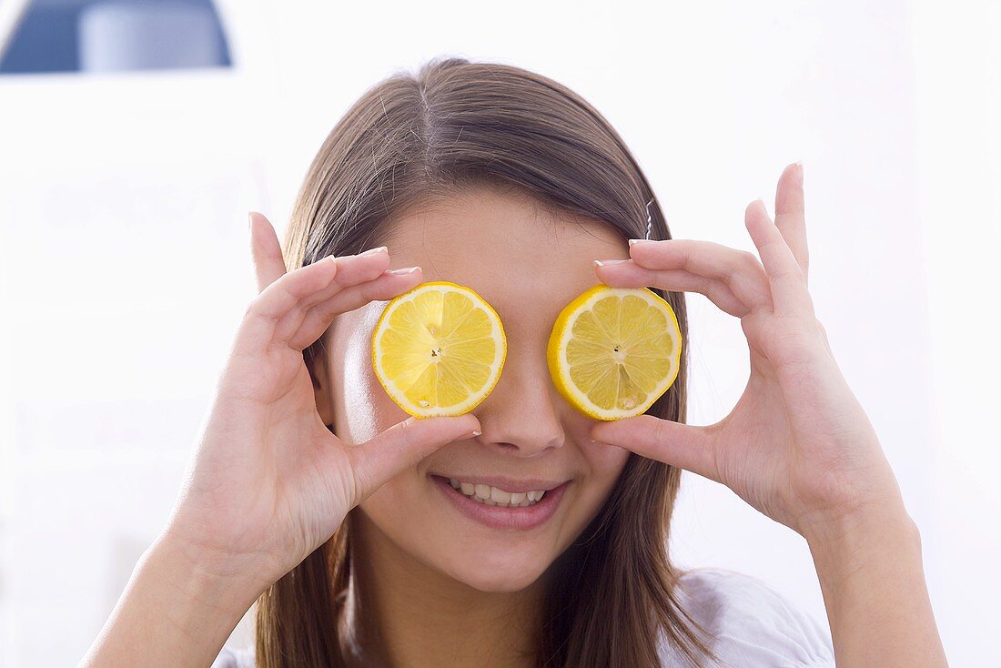 Mädchen hält Zitronenscheiben vor ihre Augen