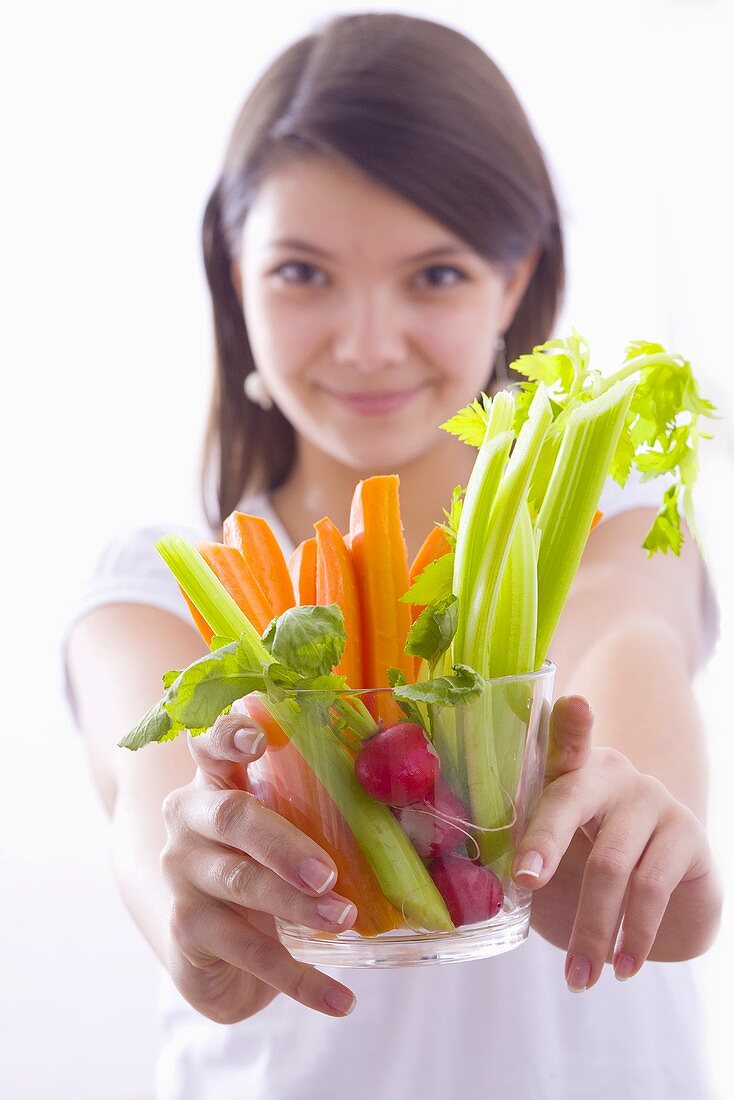 Mädchen hält Glasschale mit Gemüsesticks und Radieschen