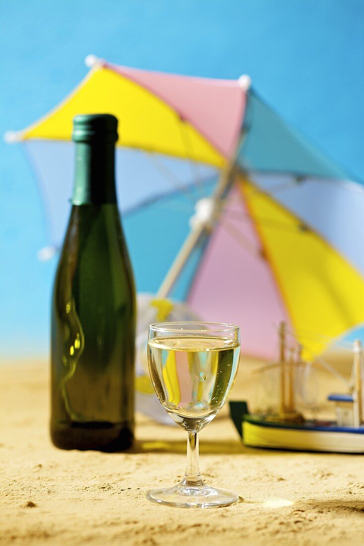 Glas und Flasche Weißwein in einer sommerlichen Kulisse