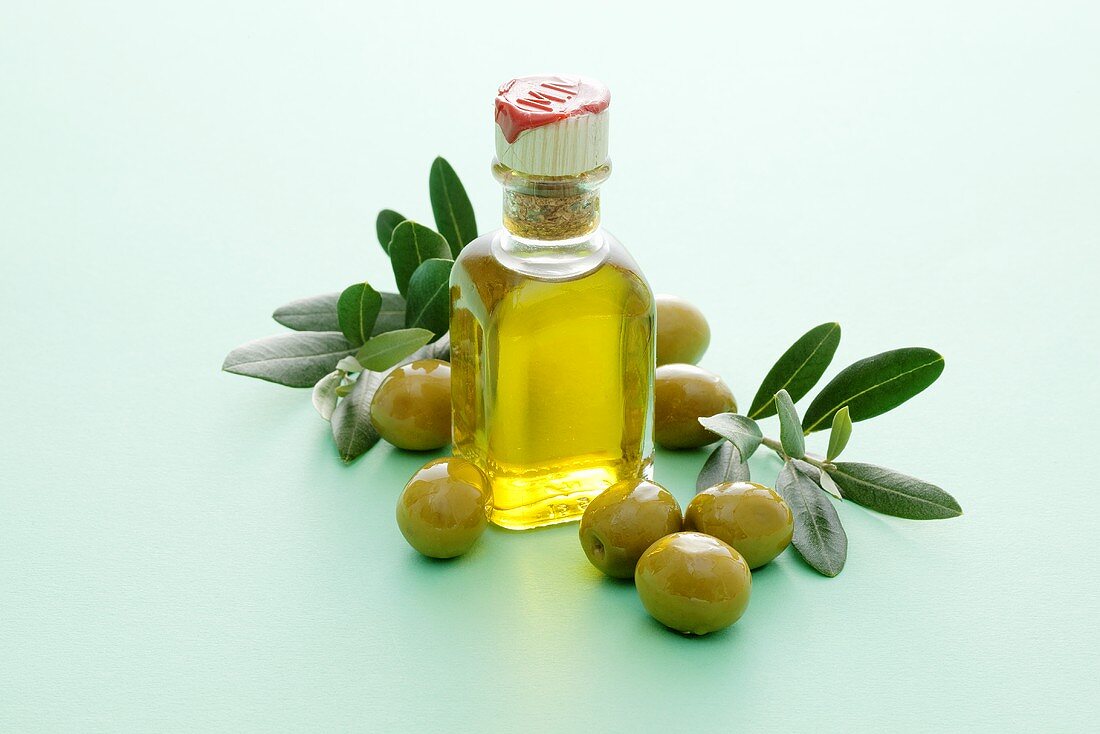 A small bottle of olive oil with olives and olive sprigs