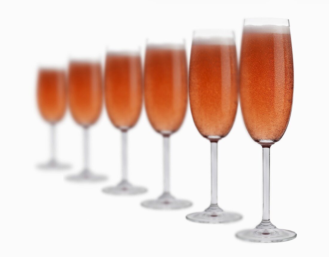 Several glasses of rosé sparkling wine in a row