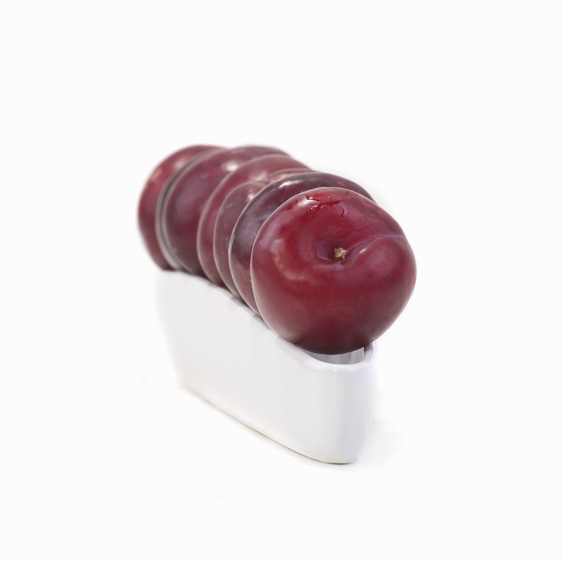 A row of plums on ceramic dish