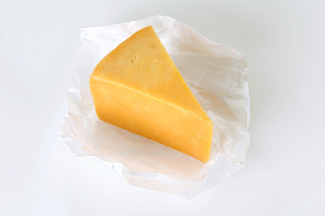 A piece of Cheddar cheese on paper