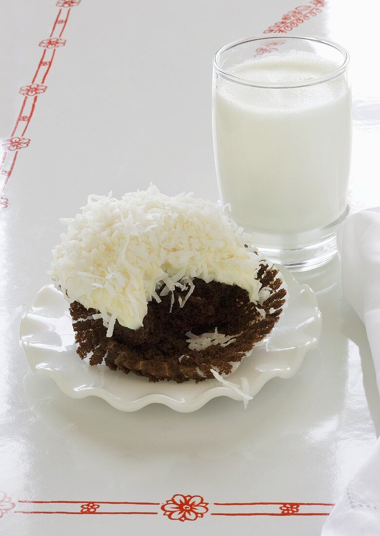 Schokoladencupcake mit Kokos (angebissen) und Glas Milch
