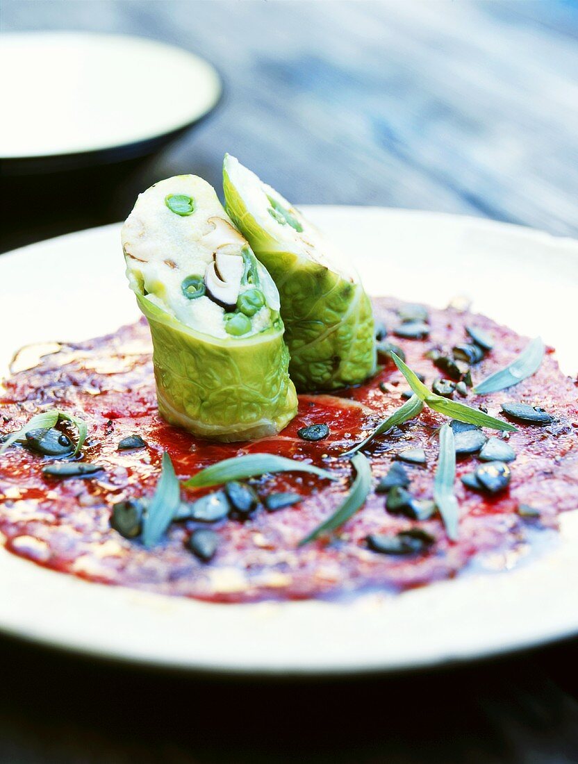 Vegetable polenta wrapped in savoy cabbage on a beef carpaccio