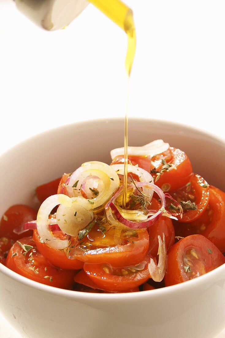 Drizzling olive oil over a tomato salad