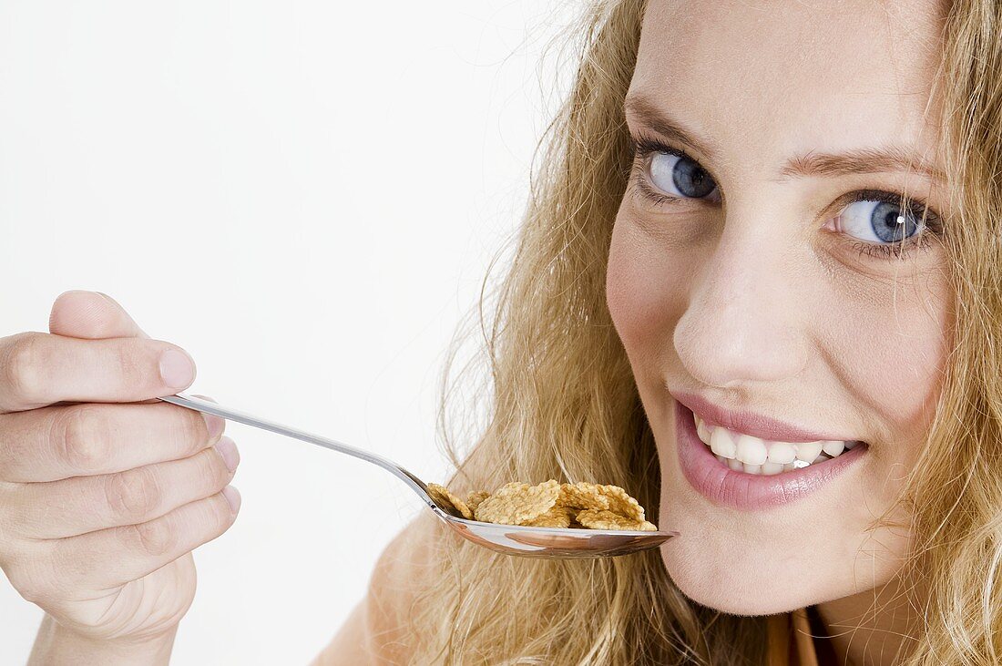 Young woman holding a spoonful of cornflakes