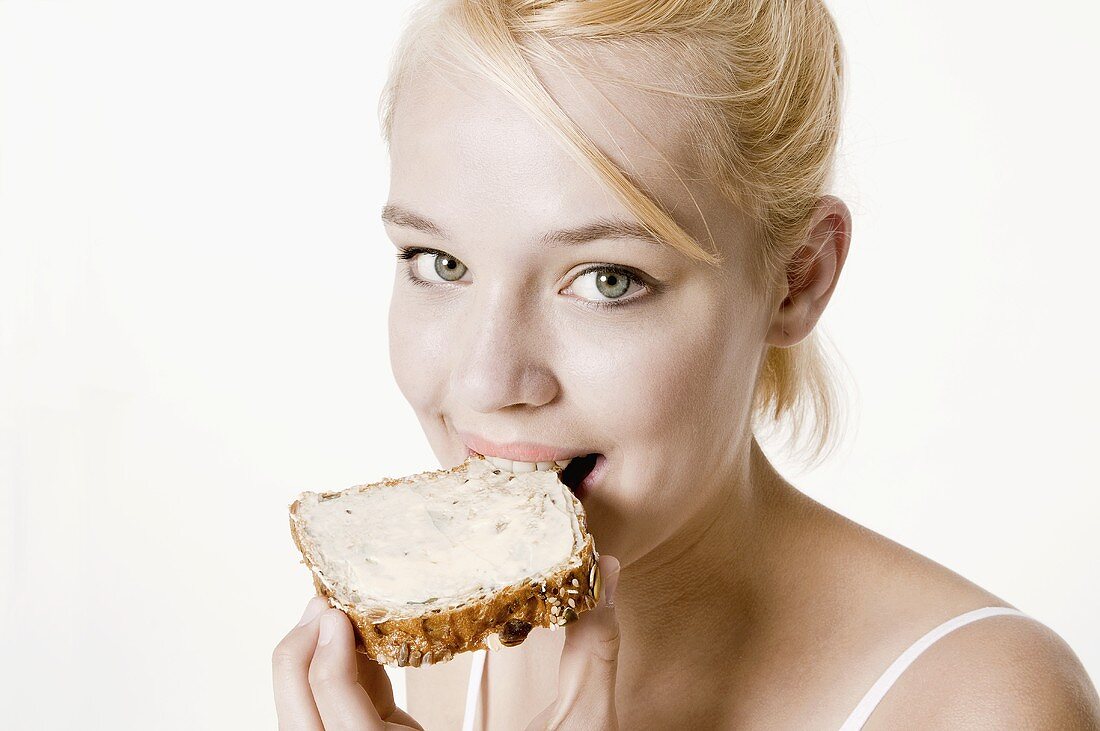Young woman biting into a slice of bread and butter