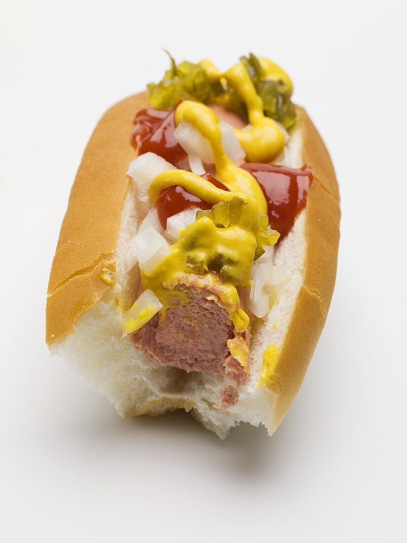 Hot Dog mit Senf, Relish, Ketchup und Zwiebeln (angebissen)