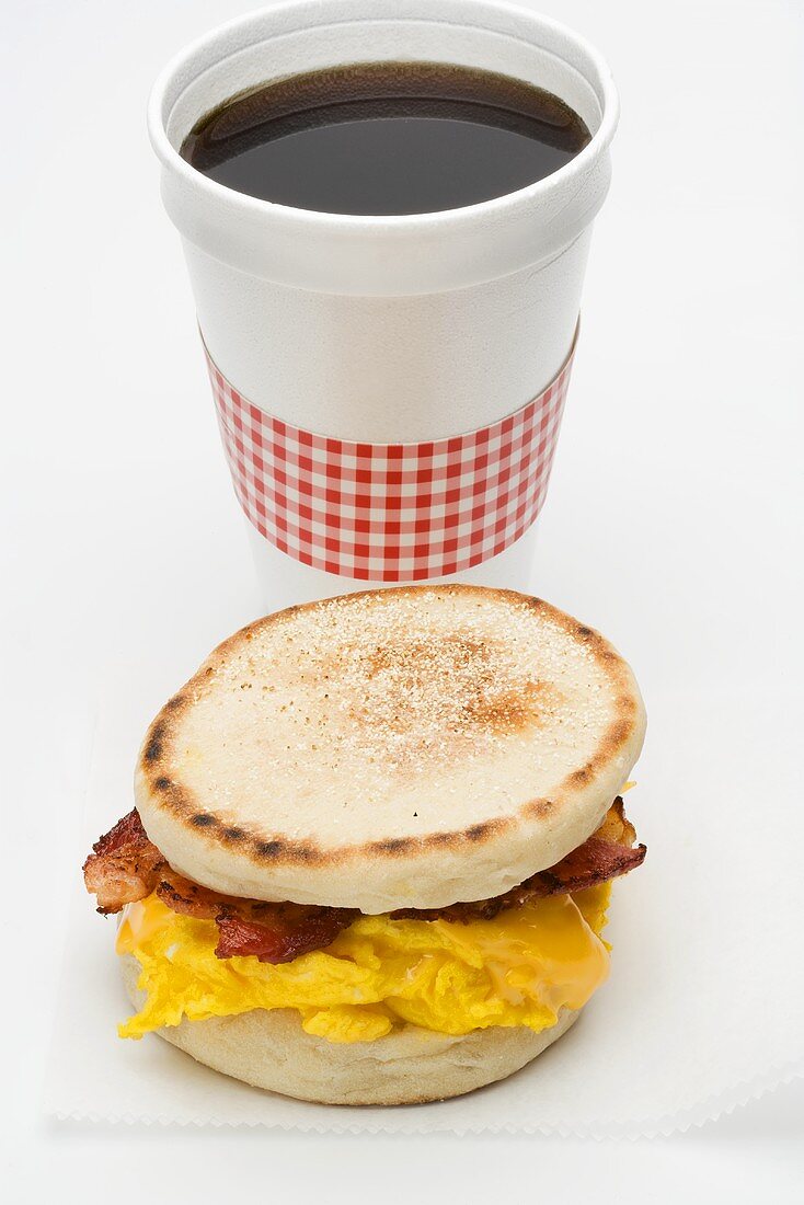 Scrambled egg and bacon in English muffin, cup of coffee